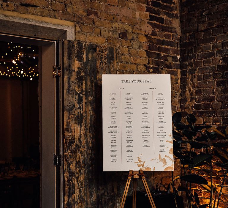 Take your Seat seating chart on a board resting on a wooden easel 