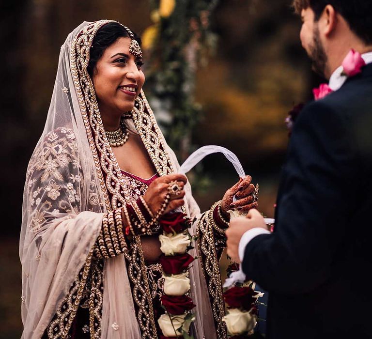 Bride smiles with detailed veil at her Autumn wedding at Minley Manor