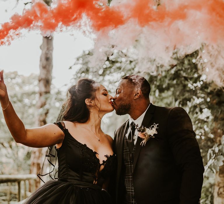 Bride holds pink smoke bomb as she kisses her husband 