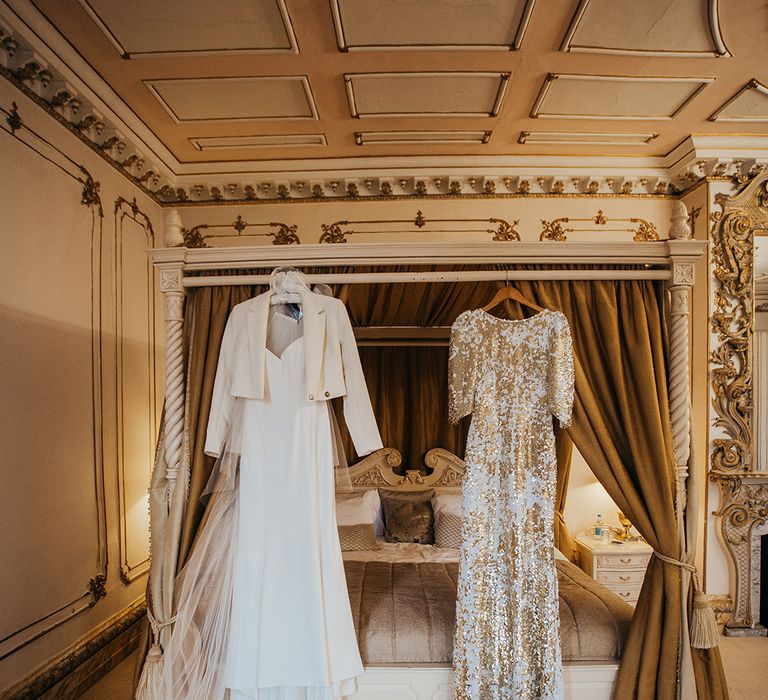 Suzanne Neville bridal gown beside Abigail Of Gardenia reception gown both hang above four poster bed 