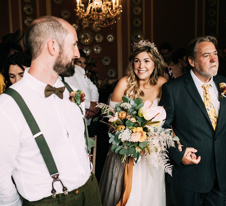 Father of the bride in yellow tie gives away his daughter with autumnal wedding bouquet