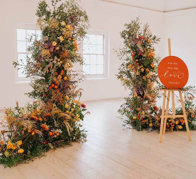 Minimalist wedding with golden wedding flowers and decor including column arrangements and orange sign on an easel