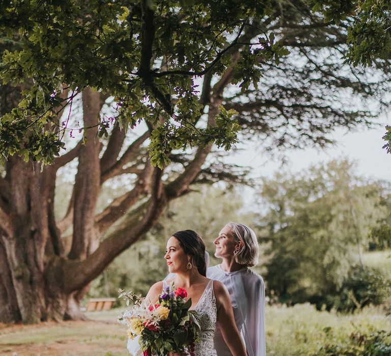 Brides walk across lake on stepping stones for their LGBTQI+ wedding in Devon 