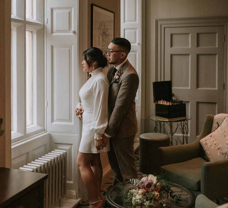 Bride and groom looking out window at Leatherhead Registry Office, Wotton House