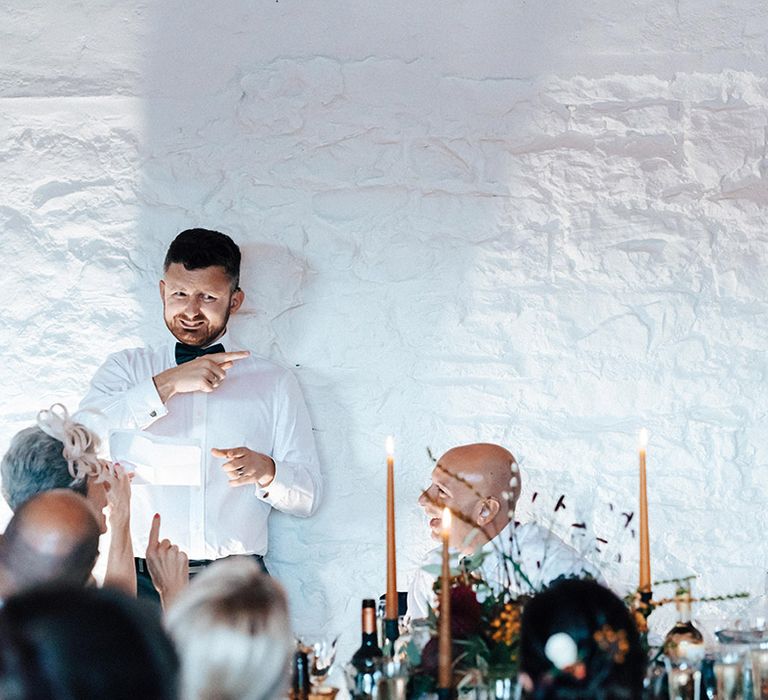 Wedding guests laugh at groomsman giving his speech in sign language for deaf attendants