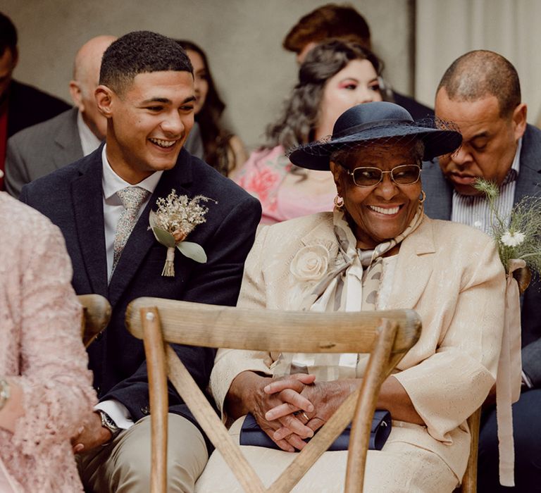 Wedding guests smile widely as they are seated for wedding ceremony