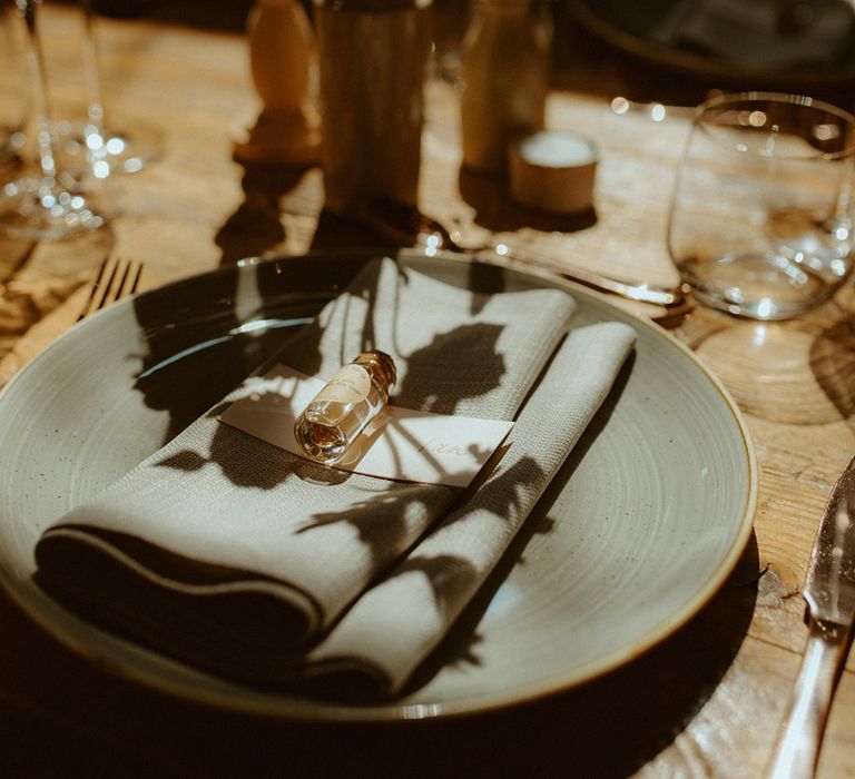 Grey plate and napkin with wedding favour with wooden vases and toffee roses