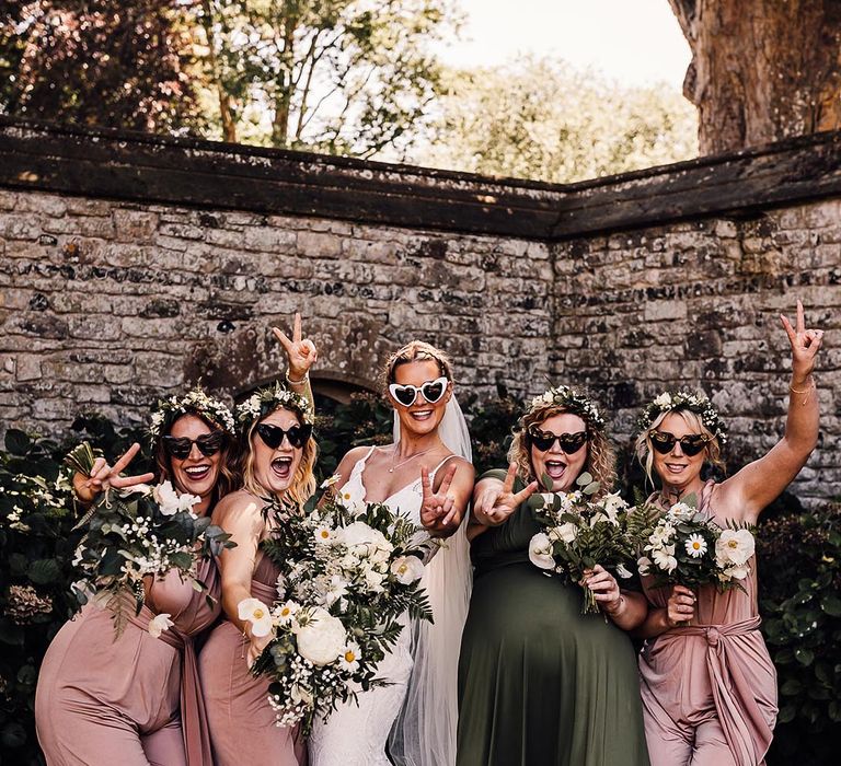 Bridal party in white heart shaped sunglasses, a lace wedding dress and pink and green bridesmaid dresses 