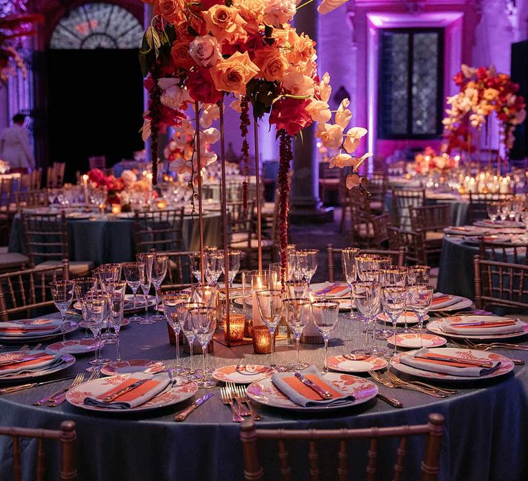 Modern floral bouquets sit in the middle of wedding reception table complete with bright coloured plates 