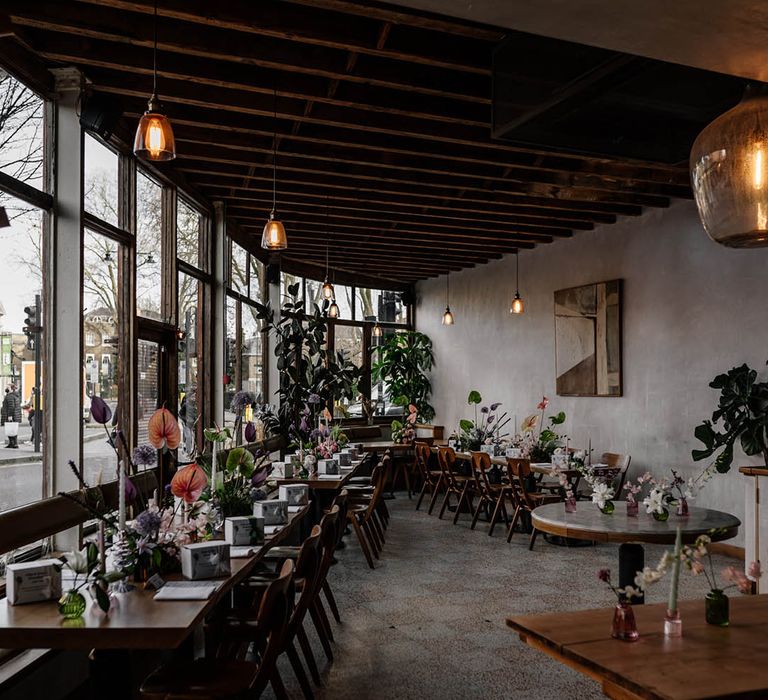 intimate wedding reception at Perilla with wooden tables decorated with pastel flowers stems including Anthuriums 