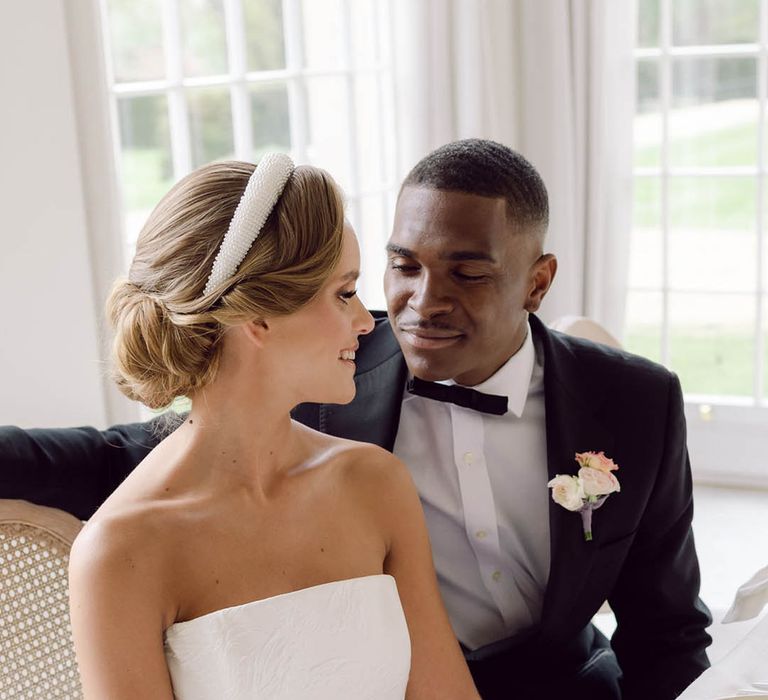 Bride in strapless brocade pattern wedding dress sitting with the groom wearing black tie for Manor House wedding 