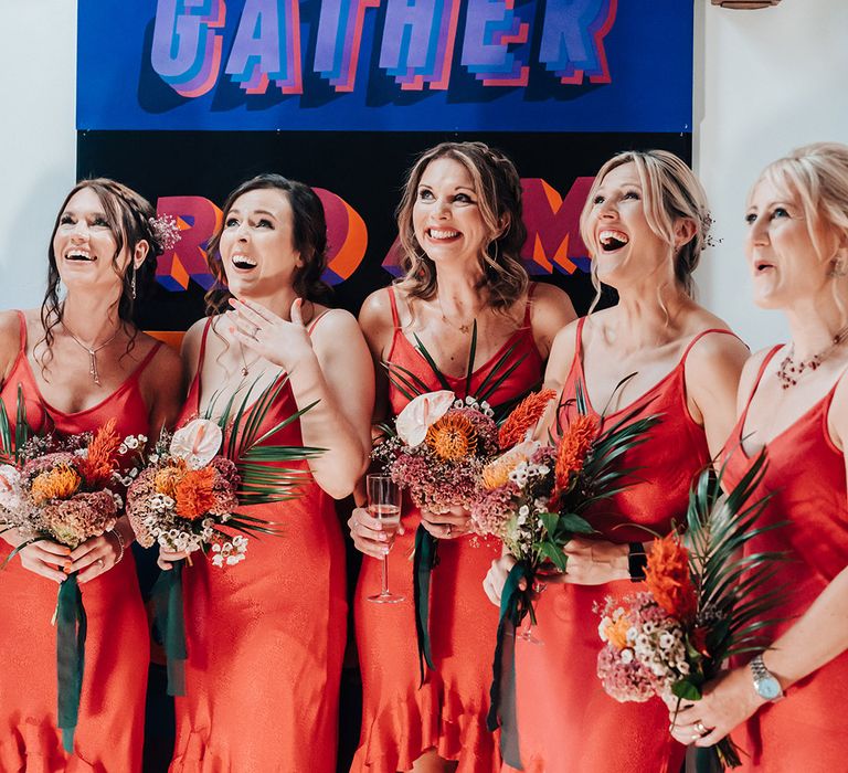 Bridesmaids in vibrant ruffle bridesmaid dresses get their first look at the bride 