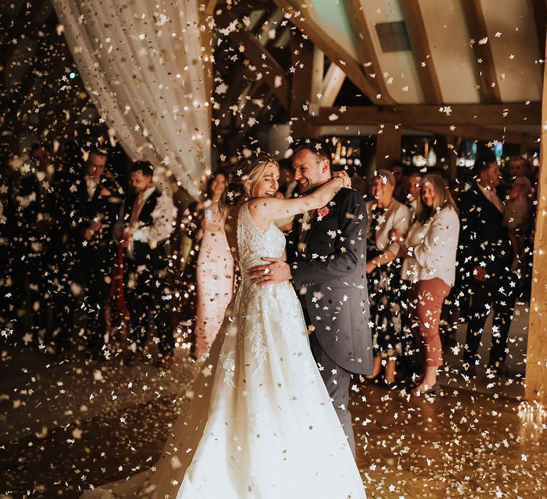 Bride and groom dance together as confetti explodes around them 