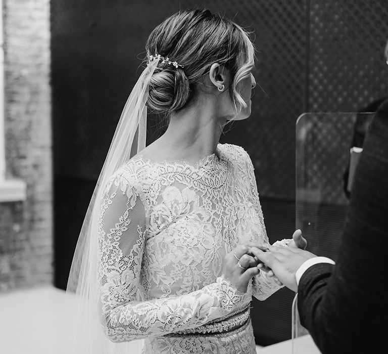 Bride wears her hair in a low bun complete with curled tendrils to the front  