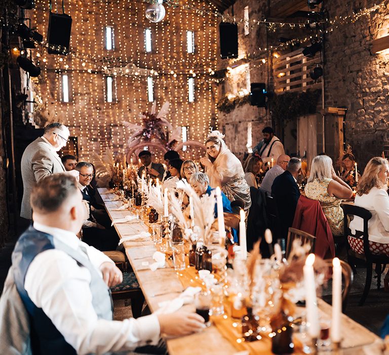 Barn wedding reception complete with fairy light canopy and wooden banquet tables