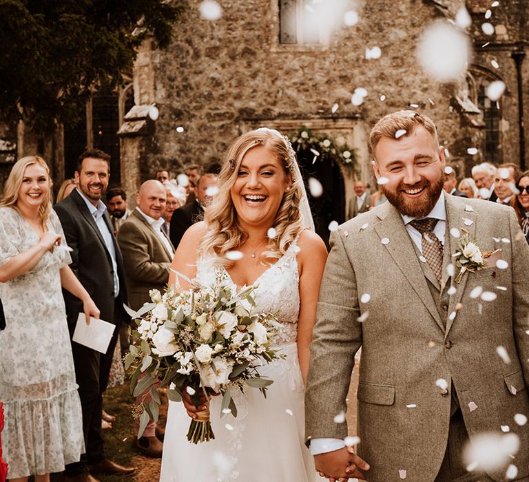 The happy couple exit their ceremony to white confetti 