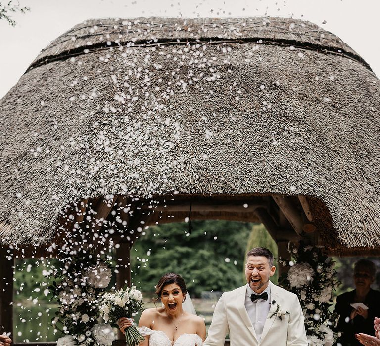 Bride and groom can't contain their excitement as they walk back down the aisle to white confetti 