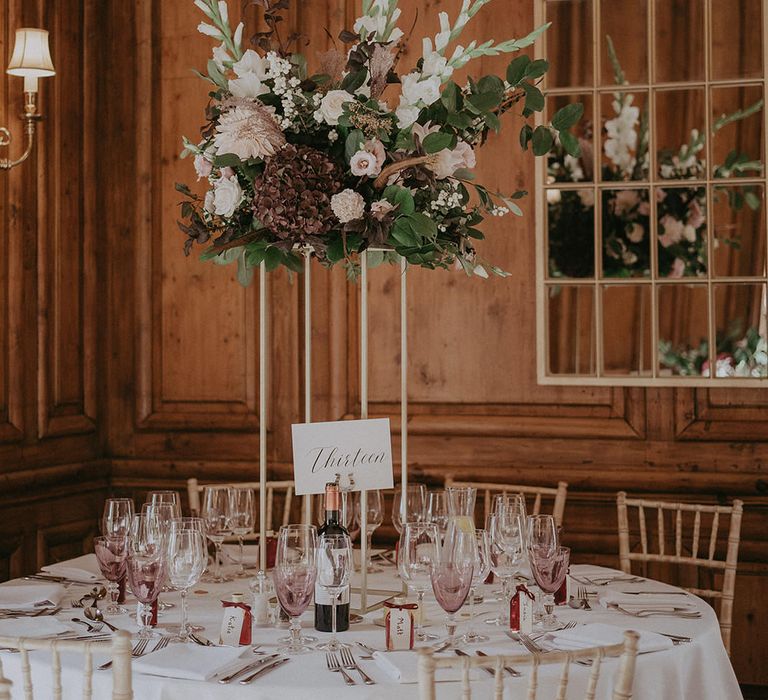 Classic floral centrepiece installation to the middle of round table covered with white tablecloth 