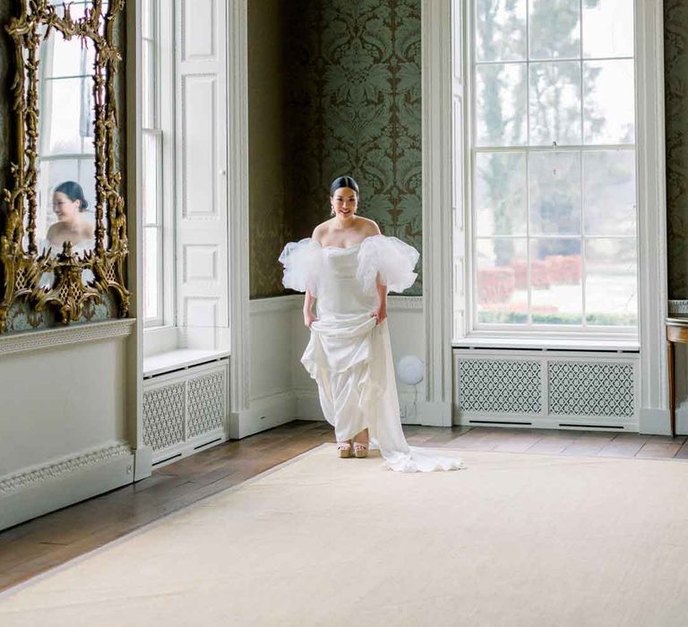 Bride in the grand reception room of St Giles House wearing strapless wedding dress with puff tulle sleeves and platform wedding heels 