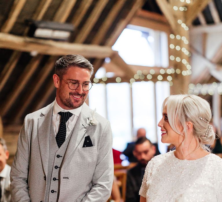 Light grey suit jacket and waistcoat with polka dotted tie smiling with the bride wearing a sparkly and tulle bridal separates 