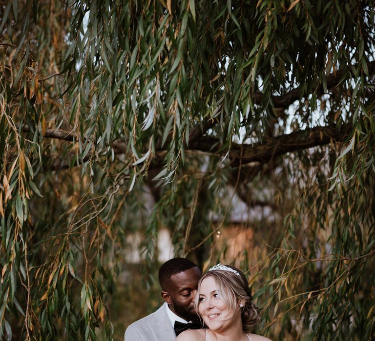 Groom embraces the bride from behind as they pose for couple portraits together 