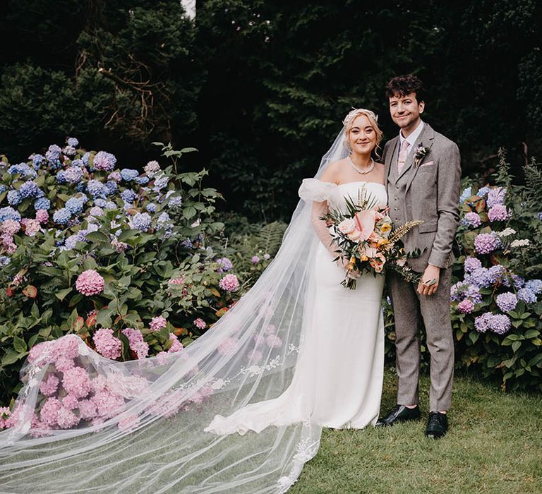 The bride wears a cathedral length veil with embroidered edge veil with groom 