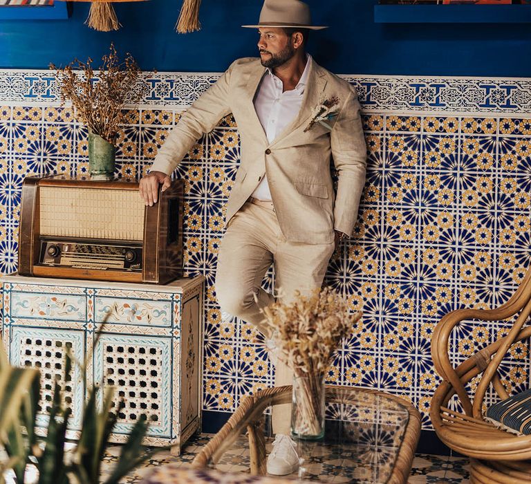 Groom wearing a beige suit and brimmed hat at Morocco wedding venue 