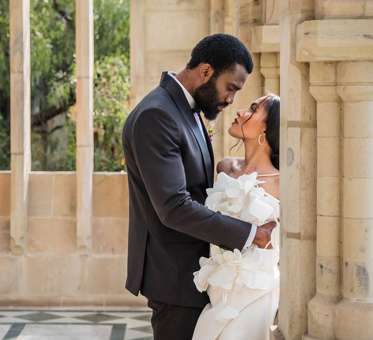 The groom wearing a black tuxedo embraces the bride for romantic wedding photo 