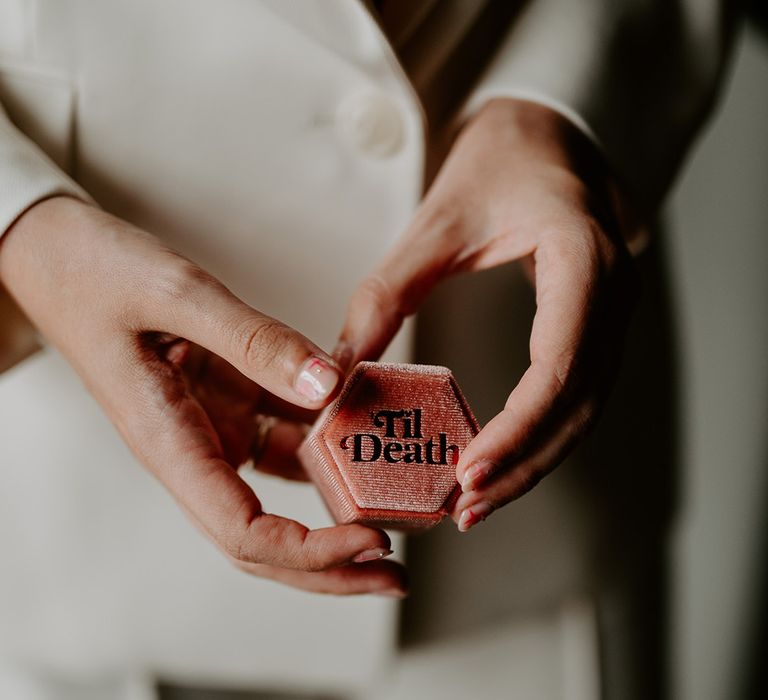 The bride holds a pink velvet 'til death ring box 