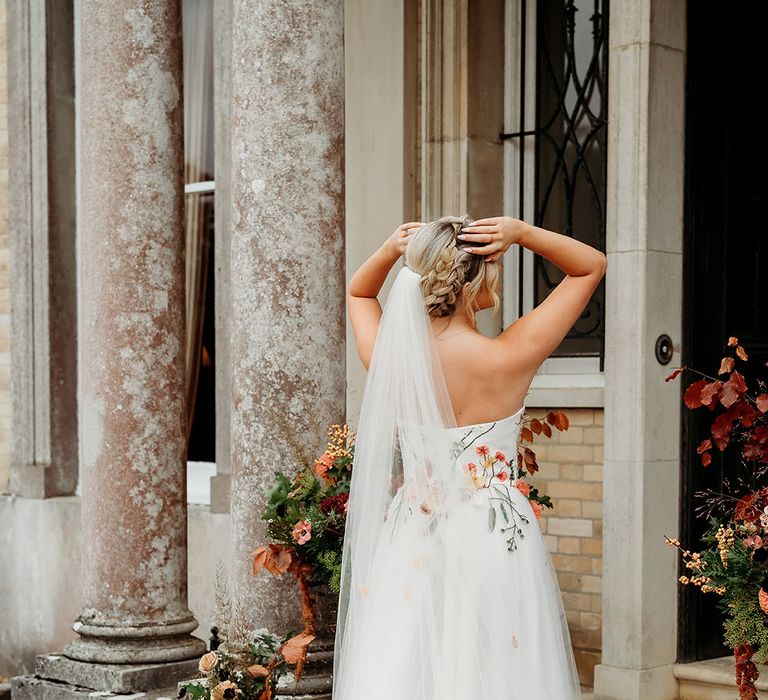 Bride wearing unique embroidered wedding veil with autumnal leaves and matching wedding dress 