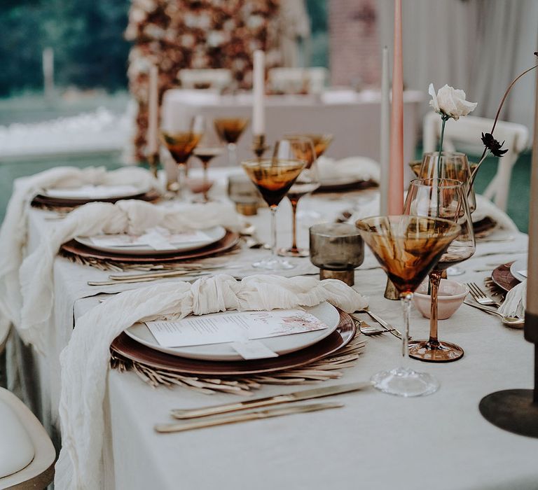 Neutral wedding tablescape in marquee with coloured glassware and simple flower arrangements 