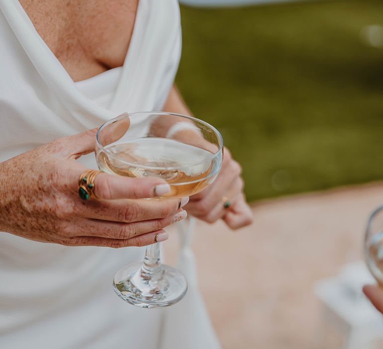 Bride in cowl neck satin wedding dress drinking wedding cocktail 