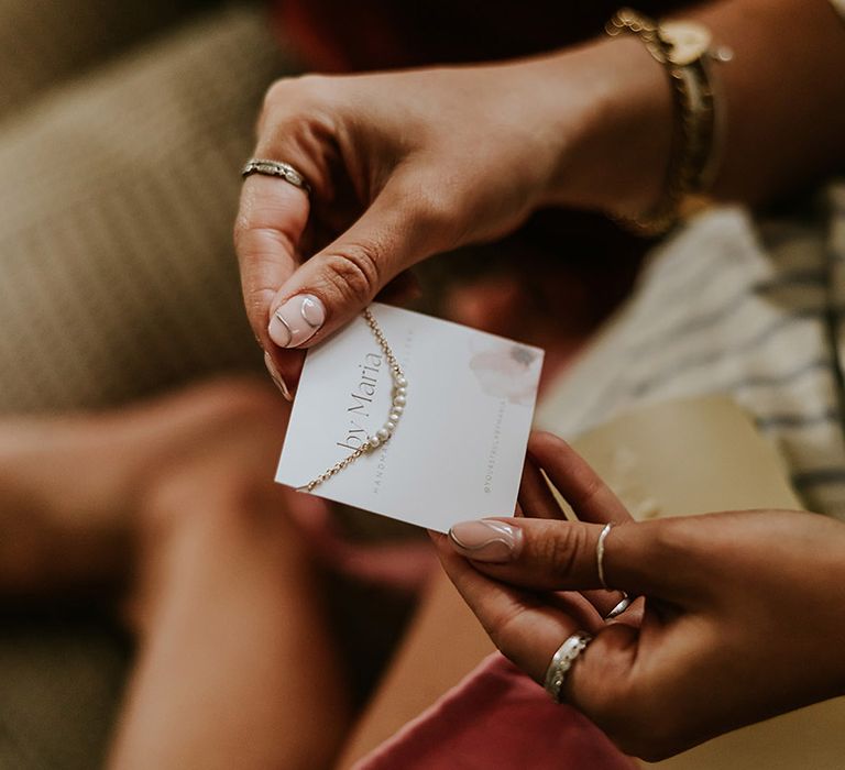 Bridesmaids open gifts from the bride on the morning of the wedding with pearl bracelets 