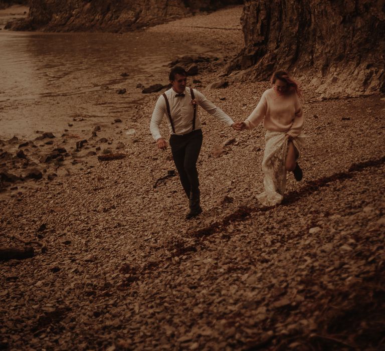 Bride and groom holding hands on the beach