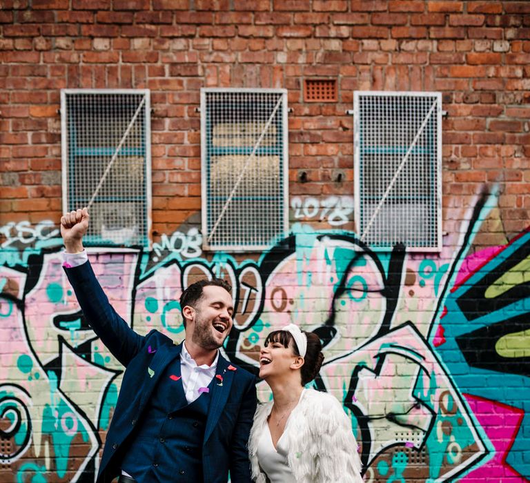 Bride and groom smiling in front of graffiti covered walls 