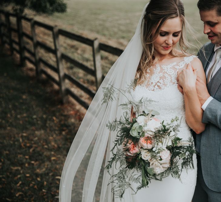 Bride in lace wedding dress and groom in grey suit for a classic wedding at Notley Abbey 