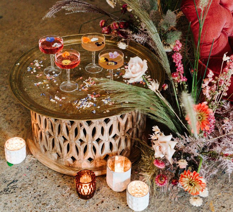 Gold platter of cocktails in coupe glasses filled with edible flowers 