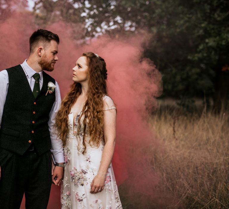 Bride & groom pose in front of pink smoke bomb