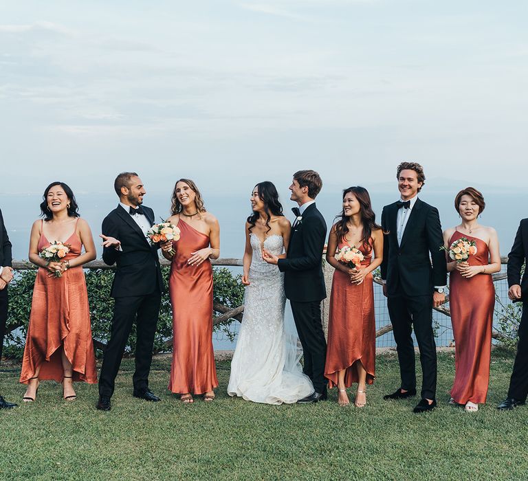 Wedding party portrait with bridesmaids in coral satin dresses 