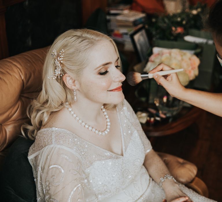 Bride having her makeup done on wedding morning