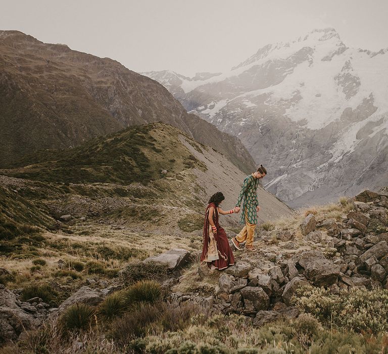 The bride and groom walking through the hills of Mount Cook, New Zealand