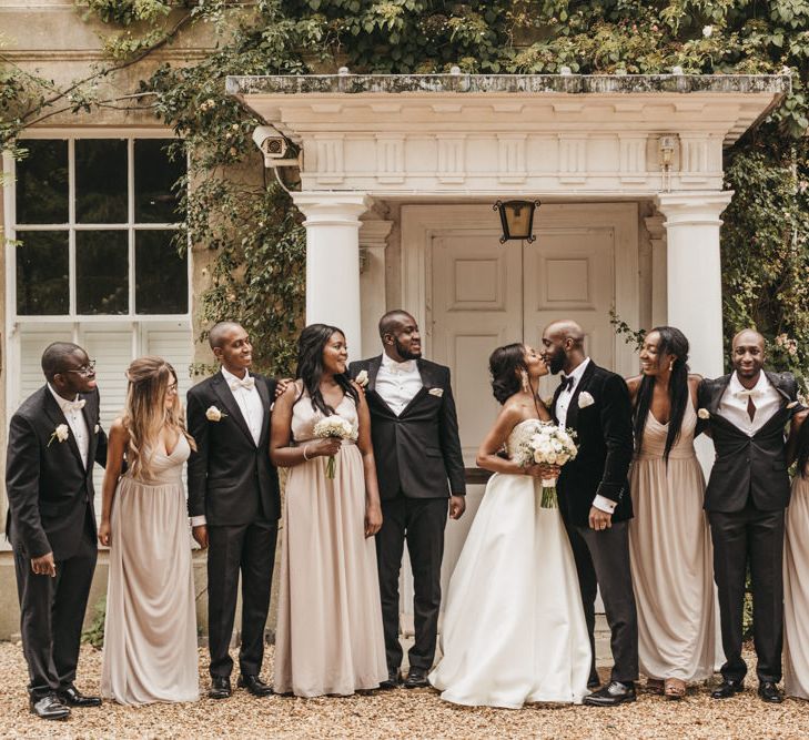 Wedding party portrait outside Northbrook Park with the bride in a Oleg Cassini wedding dress, Bridesmaids wearing dusky pink dresses and groomsmen in tuxedos and bow ties. 