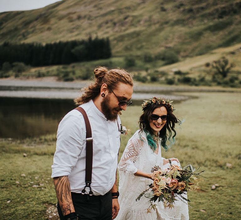 Bride & groom walk together in the Lake District both wearing dark sunglasses