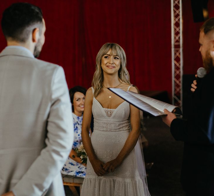 White bride with blonde fringe looking lovingly at groom during wedding ceremony