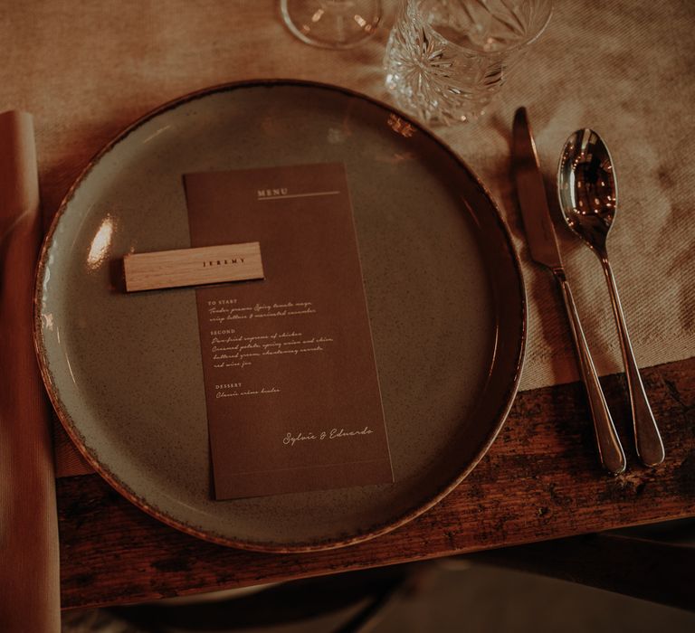 Place setting with coloured tableware, wooden name place setting and menu card 