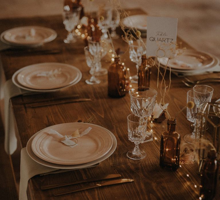 Minimalist table setting decor with dried grasses, coloured glassware and wooden table 