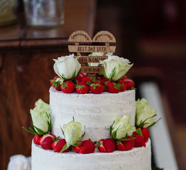 Two tier wedding cake with white frosting and strawberry decoration