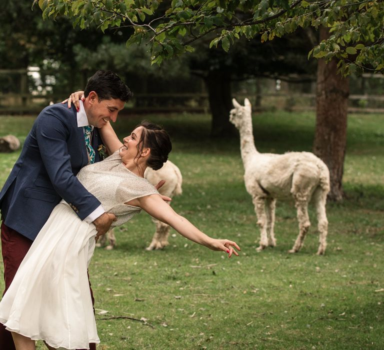 Bride & groom dance in a field with alpacas 