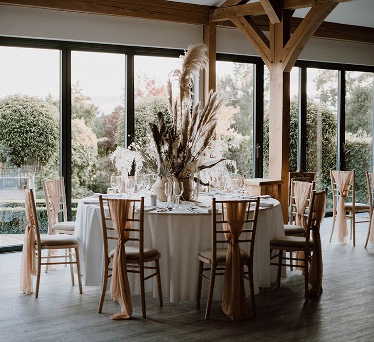 Reception at Pryors Hayes wedding venue with fabric chair backs and dried flower centrepieces 