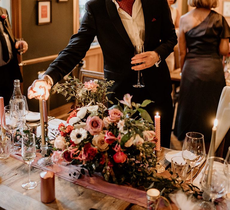 Groom lights candle during wedding reception dinner